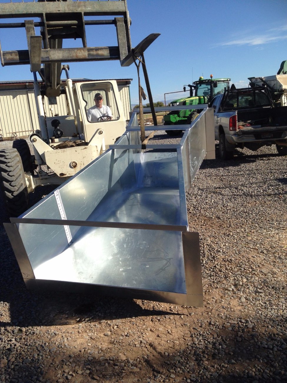 A custom galvanized steel trough, freshly fabricated and loaded onto a forklift for delivery to a farm customer